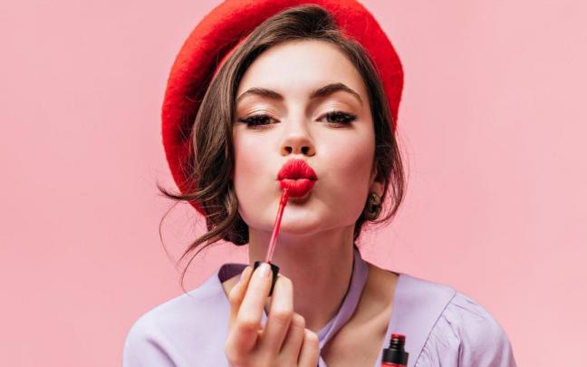 Una mujer se pinta los labios de rojo. Una mujer se pinta los labios de rojo.
