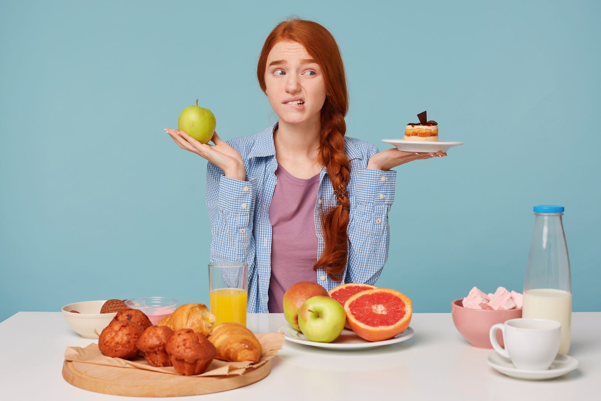 Una joven se debate entre comerse una manzana o un pastel.