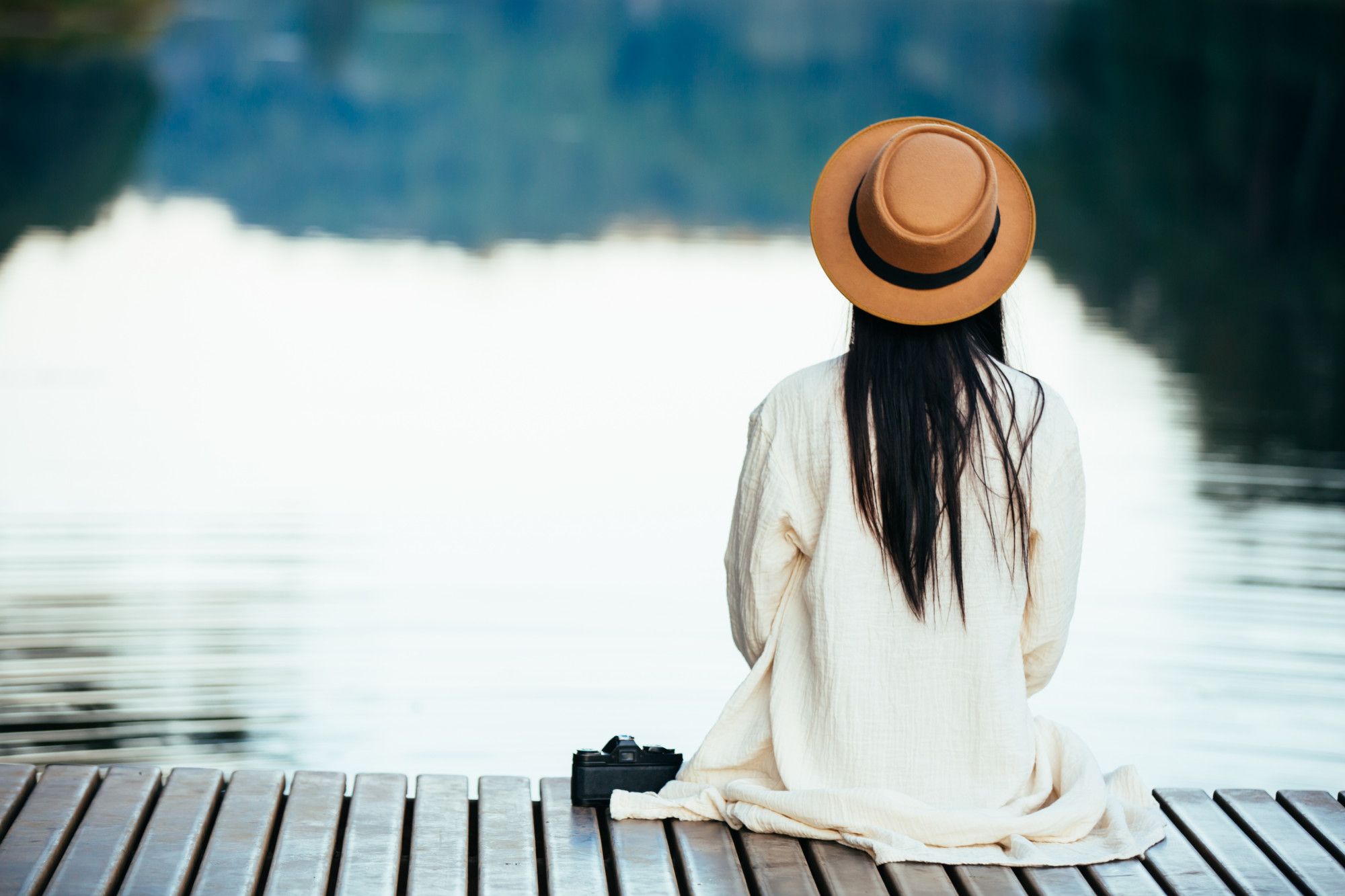 Una mujer solitaria sentada junto a un lago.