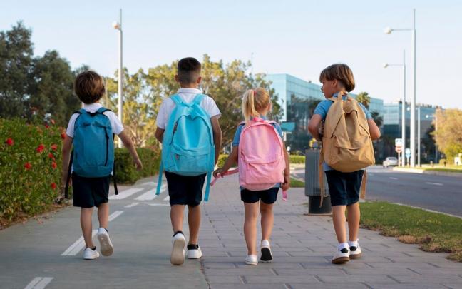 Tres niños y una niña van al colegio con la mochila a la espalda. Tres niños y una niña van al colegio con la mochila a la espalda.