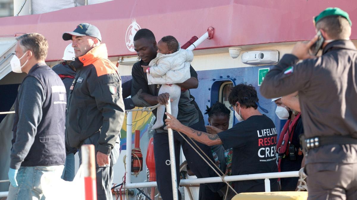 Un migrante con un bebé en brazos abandona el barco ‘Rise Above’ atracado en el puerto de Reggio Calabria.