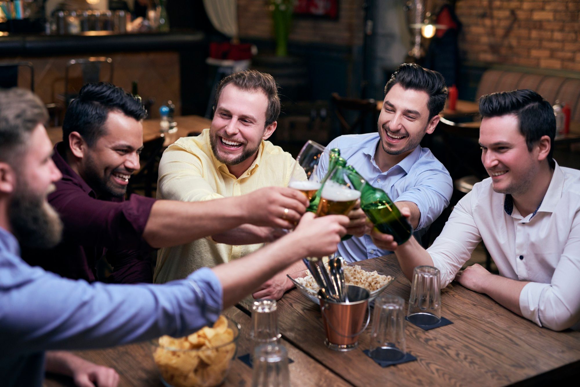Varios amigos brindan con cerveza en un bar.