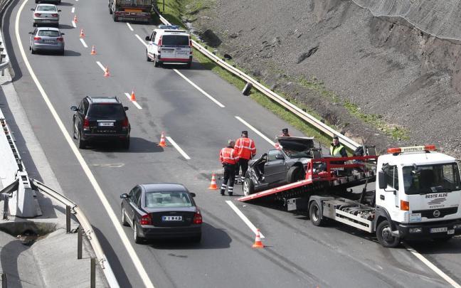 Un agente de la Unidad de Tráfico de la Ertzaintza regula el tráfico mientras la grúa retira un vehículo accidentado. Un agente de la Unidad de Tráfico de la Ertzaintza regula el tráfico mientras la grúa retira un vehículo accidentado.