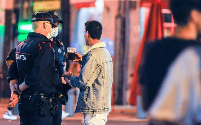 Una patrulla de la Ertzaintza conversa con un joven en la calle.