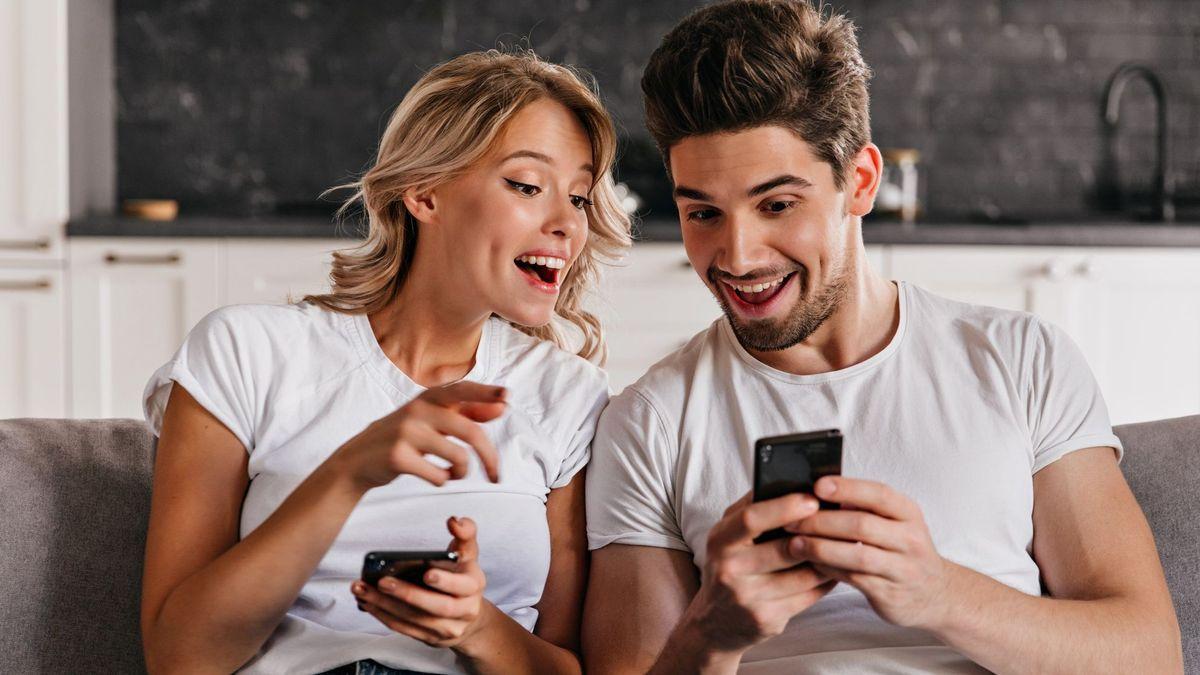 Una pareja se divierte mirando a sus móviles.