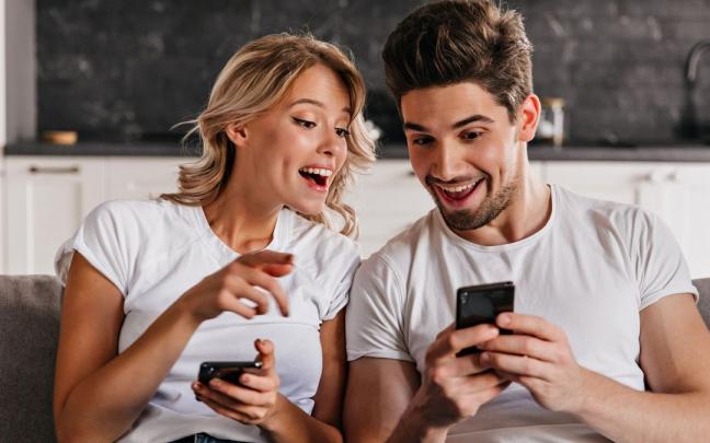 Una pareja se divierte mirando a sus móviles. Una pareja se divierte mirando a sus móviles.
