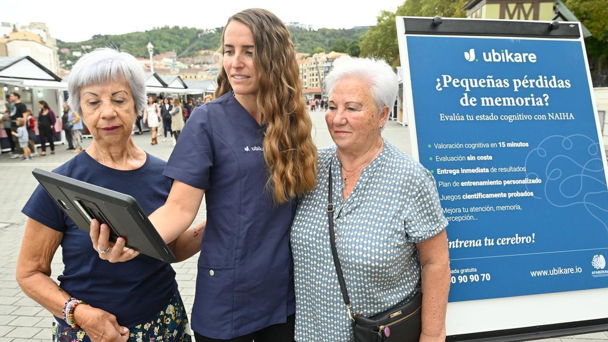 Nerea Amenabar muestra el test a dos asociadas de AFA Bizkaia.