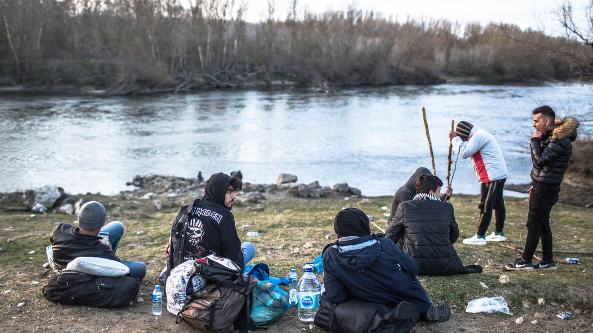 Un grupo de personas espera en el río Evros, frontera entre Grecia y Turquía.