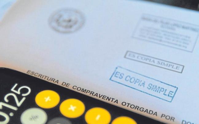 Una calculadora y una escritura de compraventa de una hipoteca Una calculadora y una escritura de compraventa de una hipoteca