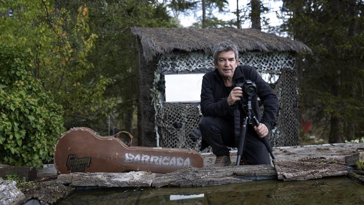 Alfredo Piedrafita, con los instrumentos del ruido y el silencio, guitarra y cámara de fotos, en su ‘estudio’ del pueblo viejo de Berriozar. Un hide con espejo espía frente a un estanque al que acuden los bichos a refrescarse.