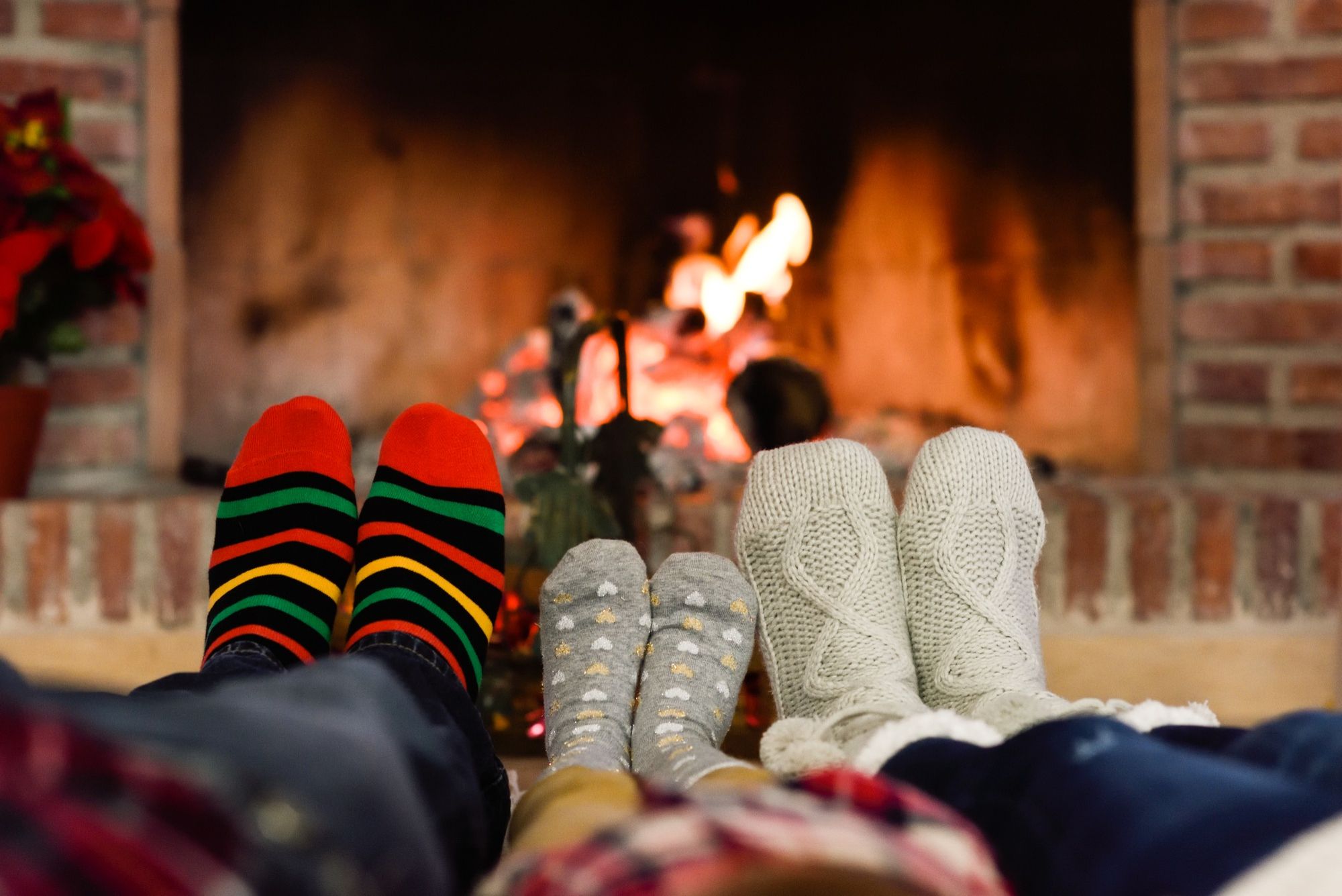 Tres personas sentadas frente a la chimenea cubren sus pies con calcetines.