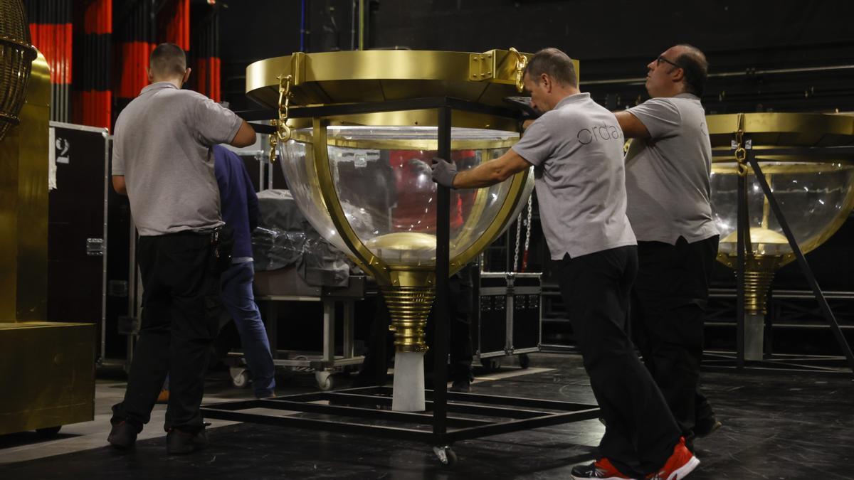 Operarios mueven los bombos de la Lotería de Navidad en el Teatro Real