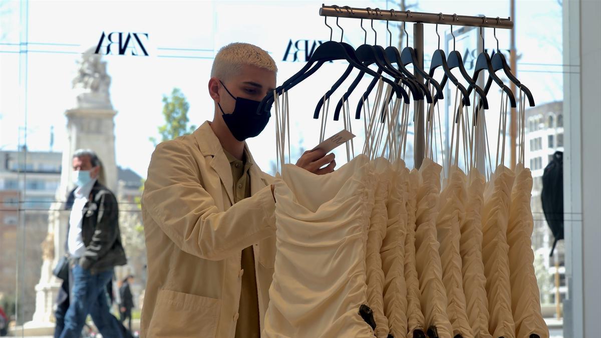Un dependiente coloca varias prendas de ropa en una tienda de Zara.