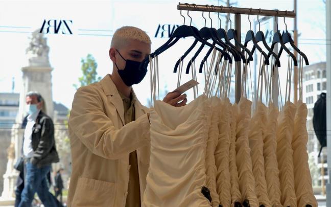 Un dependiente coloca varias prendas de ropa en una tienda de Zara. Un dependiente coloca varias prendas de ropa en una tienda de Zara.