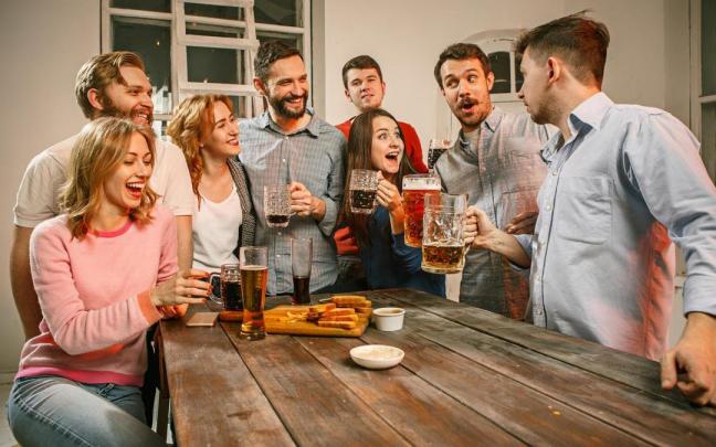 Chicos y chicas se divierten mientras toman unas cervezas.