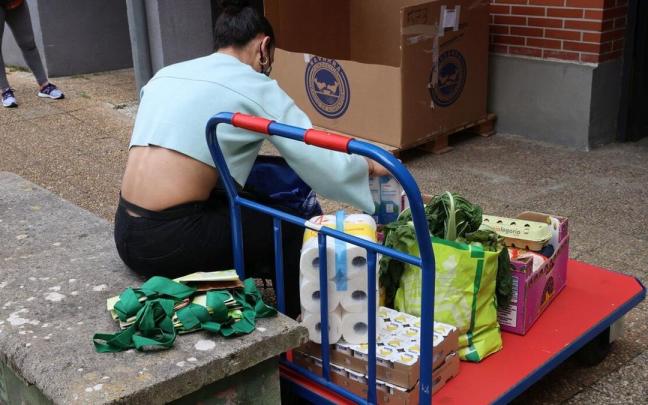 Una mujer recibe alimentos en el punto municipal de reparto de Ermitaga&ntilde;a.