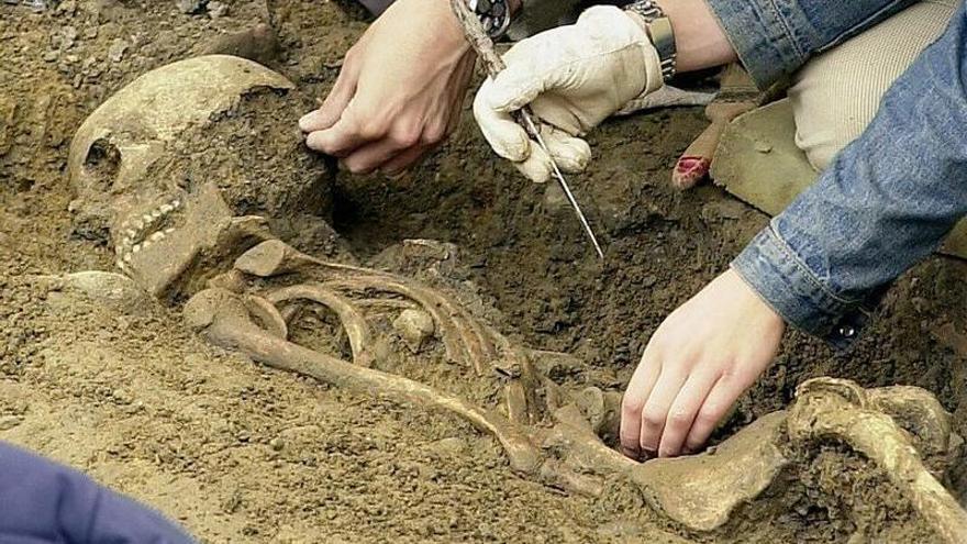 Dos arque&oacute;logos limpian de tierra uno de los esqueletos aparecidos en la excavaci&oacute;n de la Plaza del Castillo