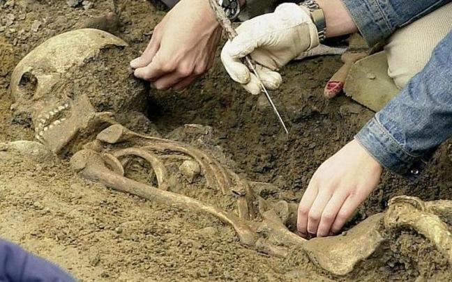 Dos arque&oacute;logos limpian de tierra uno de los esqueletos aparecidos en la excavaci&oacute;n de la Plaza del Castillo