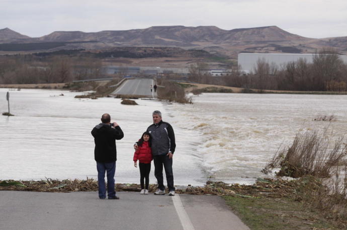 Vecinos se fotografían junto al tramo de la carretera NA - 5202, cortado por la riada del Ebro tras las fuertes lluvias de 2013