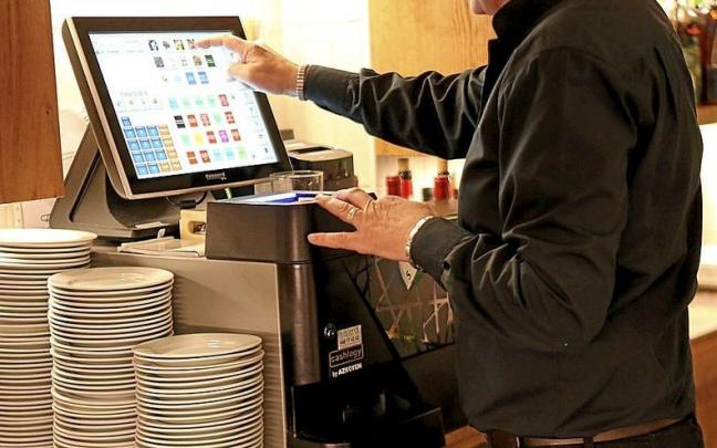 El empleado de un establecimiento emite una factura en una caja registradora. El empleado de un establecimiento emite una factura en una caja registradora.
