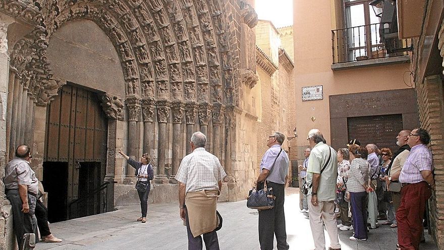 Un grupo de turistas atiende las explicaciones sobre la Puerta del Juicio de la Catedral de Tudela.