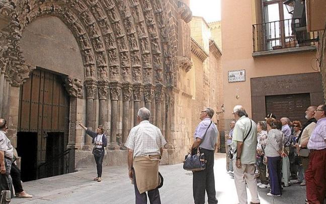 Un grupo de turistas atiende las explicaciones sobre la Puerta del Juicio de la Catedral de Tudela.