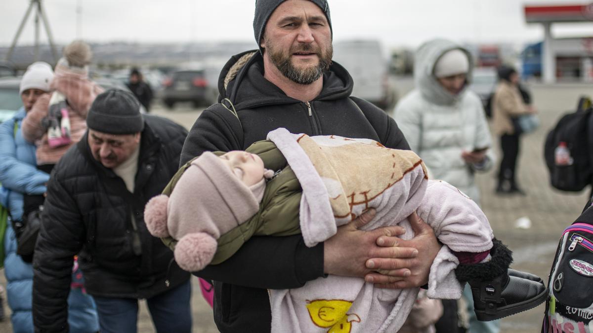 Un hombre con un niño en brazos en el paso fronterizo de Porubne, en el oeste de Ucrania.
