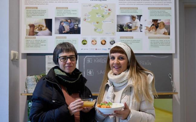 Laura Aguirre y Chiara Rotolo, madres de la Escuela Infantil Izartegi, posan ante el cartel del programa 'Hemengoak', con algunos platos del men&uacute;.