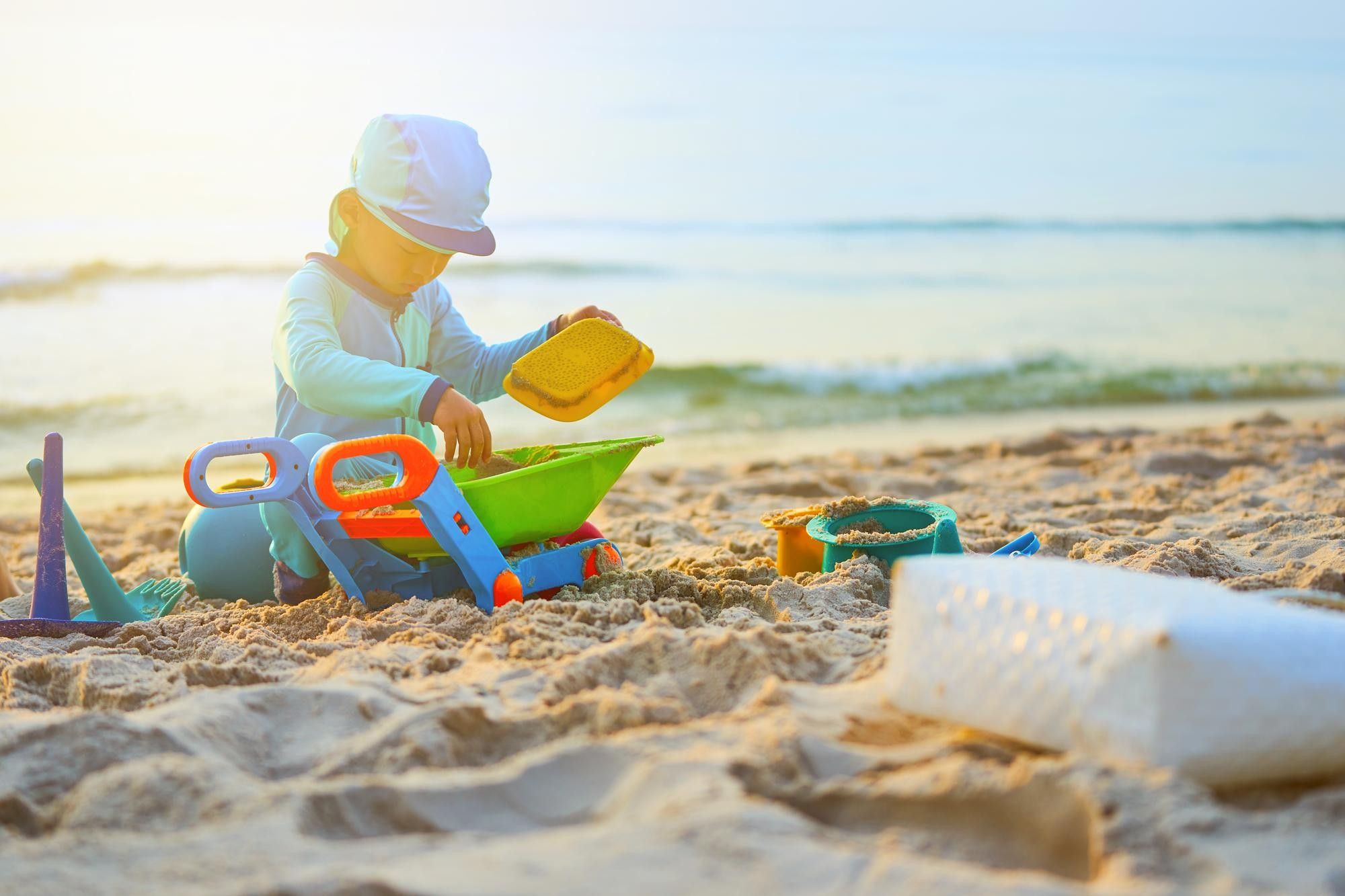 Un niño juega en la playa bien protegido.