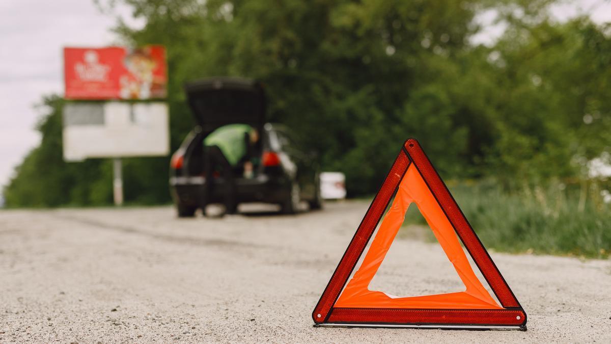 Triángulo en una carretera señalizando la incidencia en un coche.