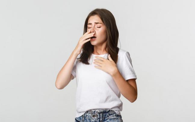 Una mujer con los ojos cerrados a punto de estornudar.