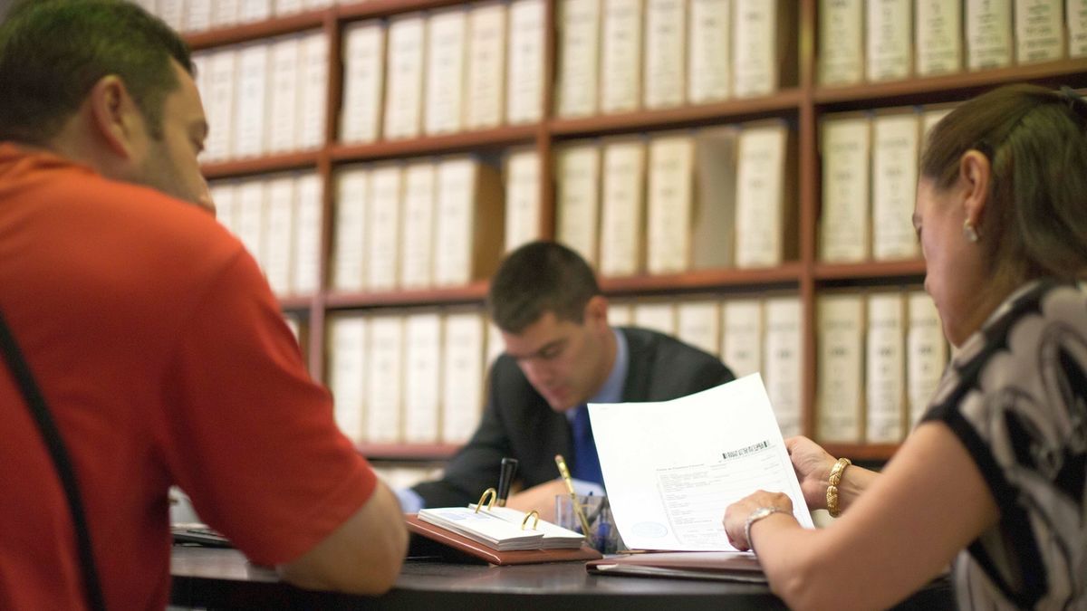 Personas ajenas a esta información repasando el contenido de un testamento en una Notaría.