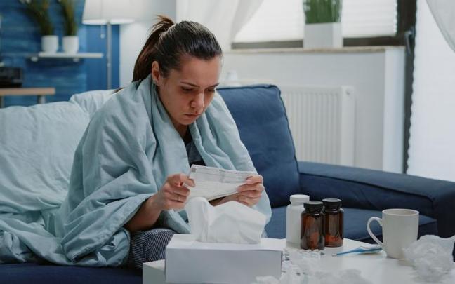 Una mujer lee el prospecto de un medicamento.