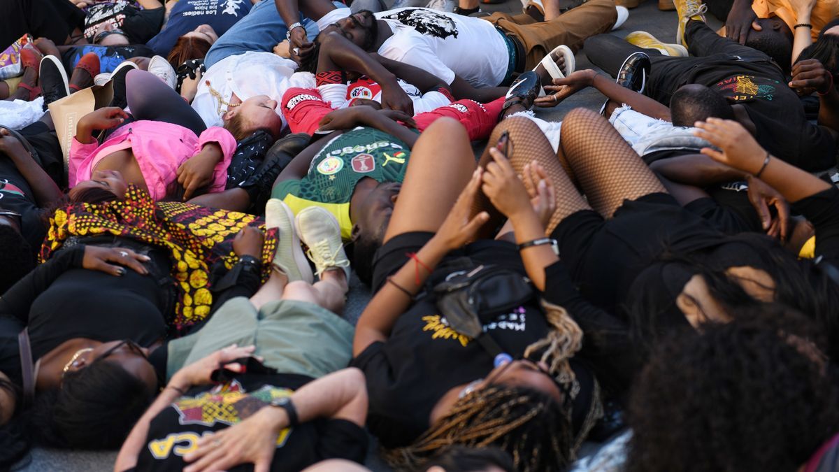 Varias personas tumbadas en el suelo durante una manifestación contra las políticas migratorias.