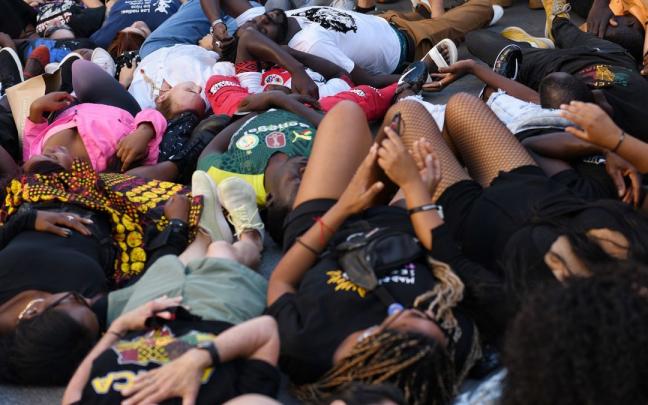 Varias personas tumbadas en el suelo durante una manifestación contra las políticas migratorias.
