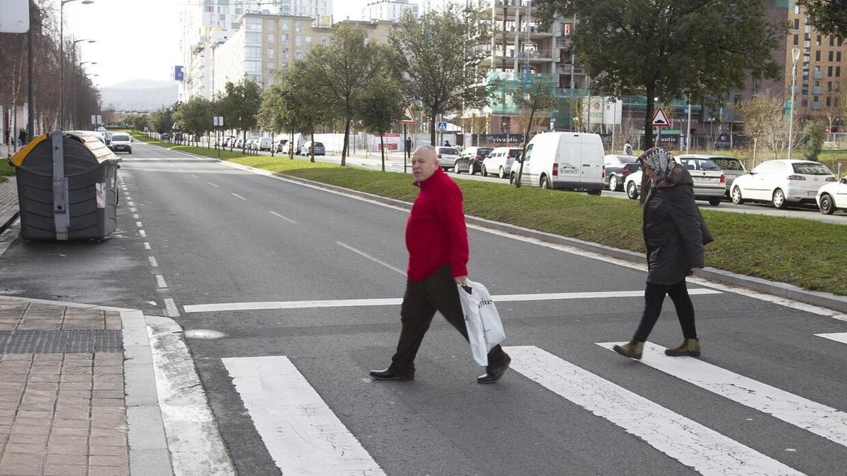 Dos personas, ajenas a la información, cruzan por un paso de cebra de la Avenida Reina Sofía