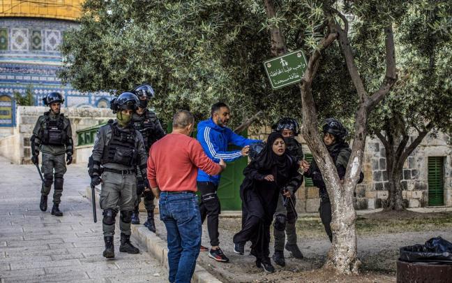 Fuerzas de seguridad israel&iacute;es empujan a una mujer palestina en la mezquita Al Aqsa.