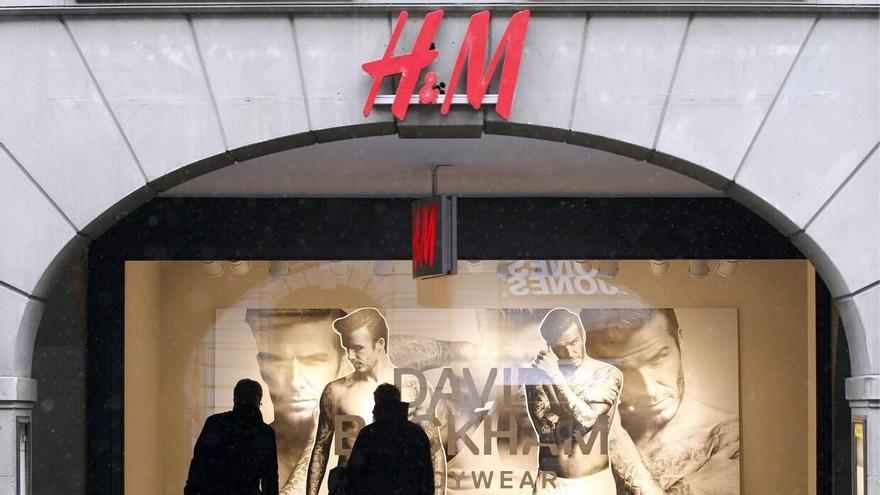 Varias personas miran un escaparate de H&M.
