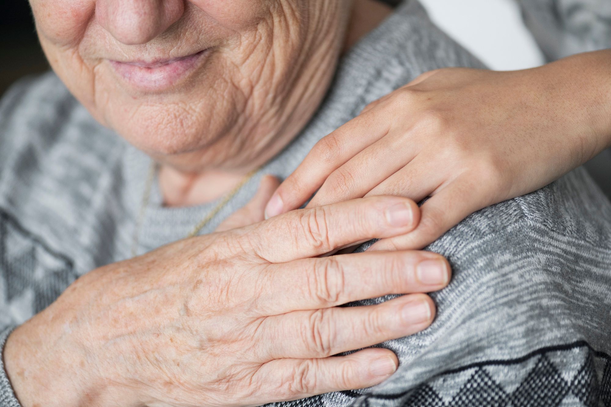 Una cuidadora pone su mano sobre el hombro de una anciana.