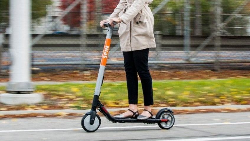 Una mujer, en patinete