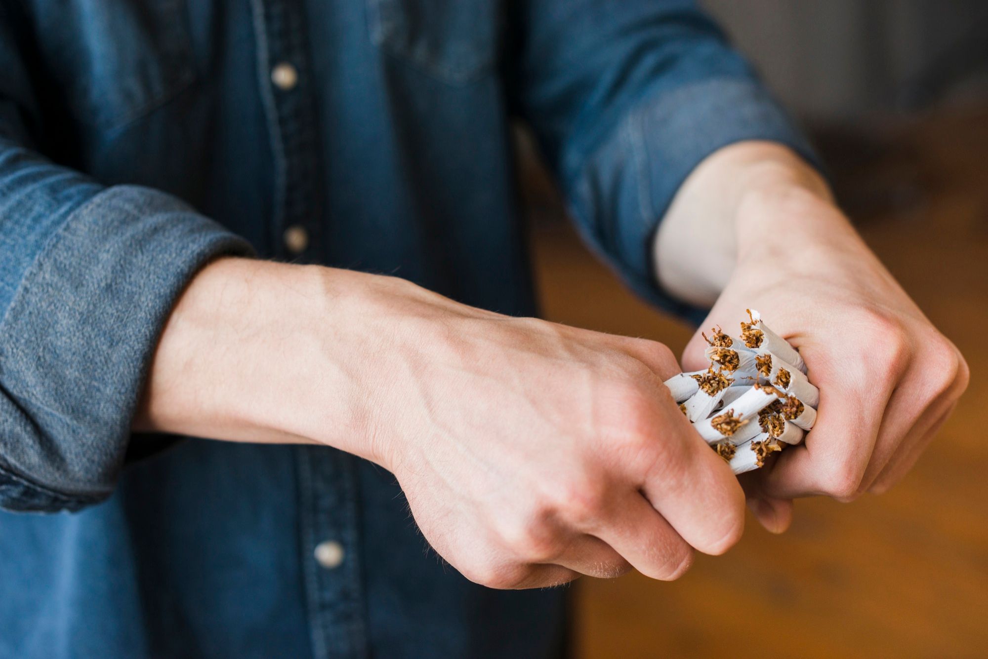 Un hombre rompe varios cigarrillos con sus manos.