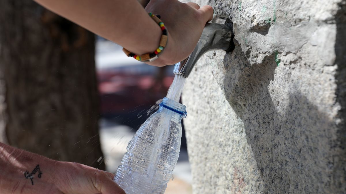 Una mujer rellena una botella de agua en una fuente, en una foto de archivo.