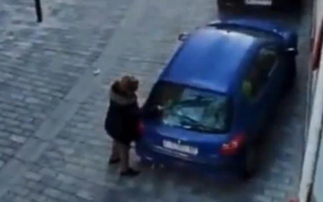 La mujer, rompiendo la luna del coche. La mujer, rompiendo la luna del coche.
