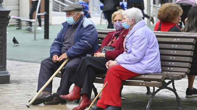 Mayores sentados en un banco con mascarilla
