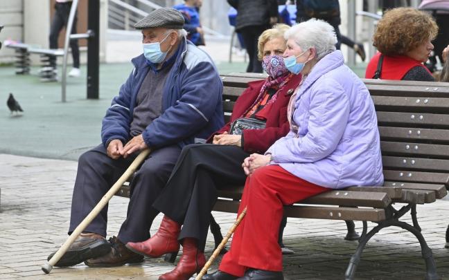 Mayores sentados en un banco con mascarilla Mayores sentados en un banco con mascarilla