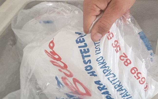 Una persona coge una bolsa de cubitos de hielo. Una persona coge una bolsa de cubitos de hielo.