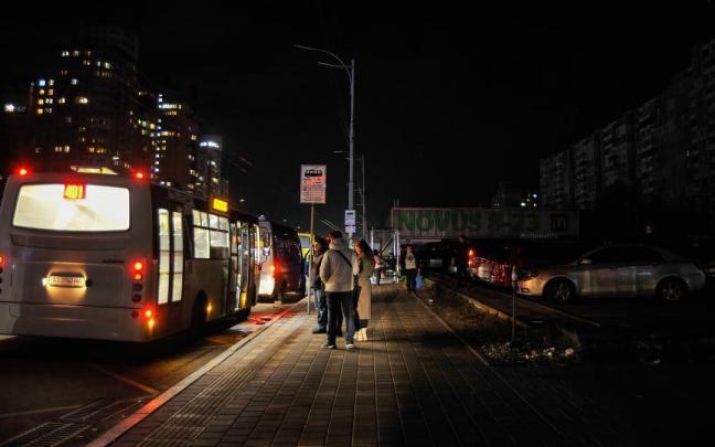 Varias personas hacen cola ante un autob&uacute;s en Kiev.