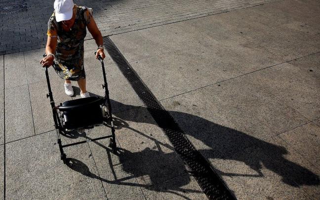Una mujer mayor paseando con un andador bajo el sol durante una ola de calor.