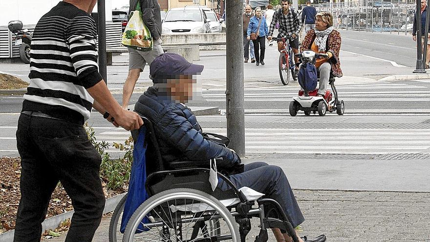 Un cuidador ajeno a esta información transporta a una persona en silla de ruedas en Vitoria. | FOTO: JOSU CHAVARRI