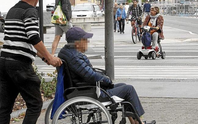 Un cuidador ajeno a esta información transporta a una persona en silla de ruedas en Vitoria. | FOTO: JOSU CHAVARRI